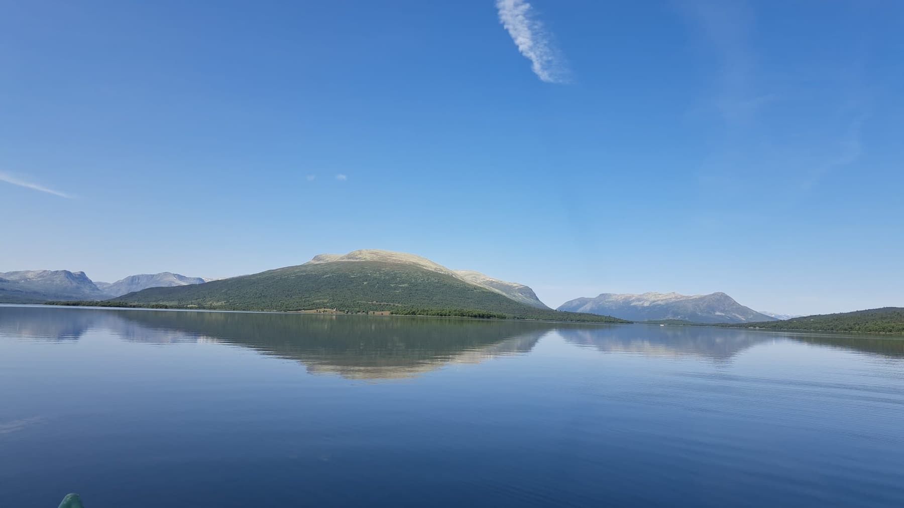 Still mountain lake reflecting snow-capped fjells in Norway