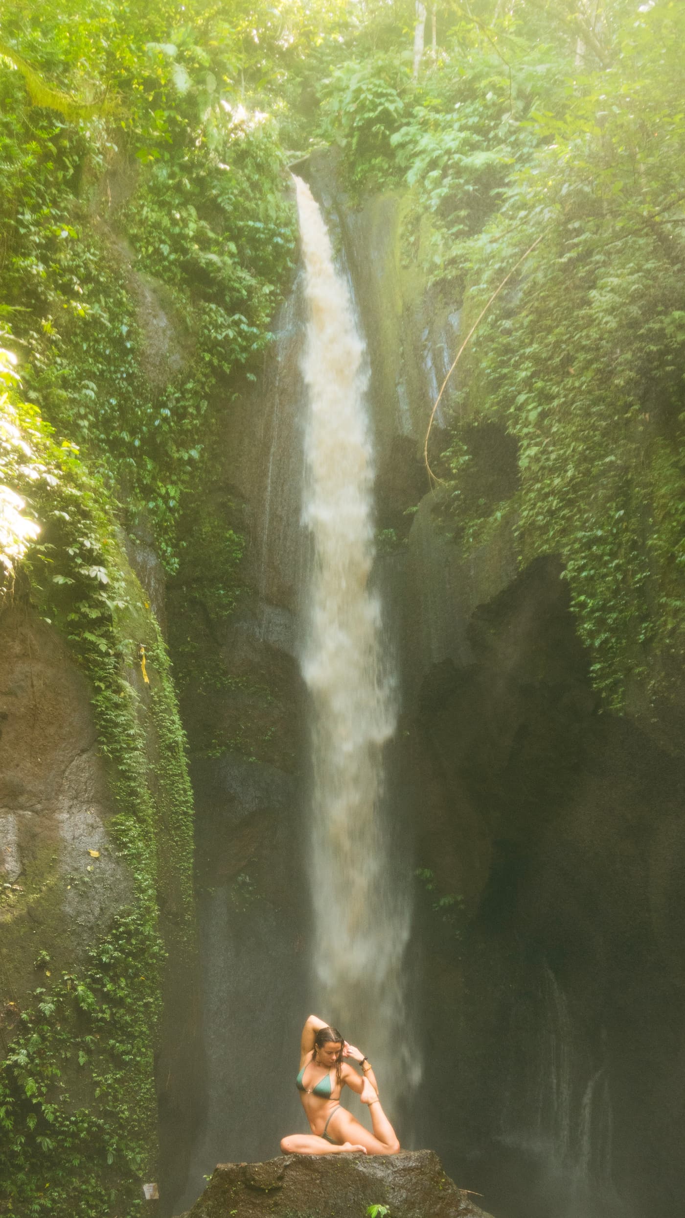 Boyana Vancheva in mermaid pose on a rock beneath a Balinese jungle waterfall