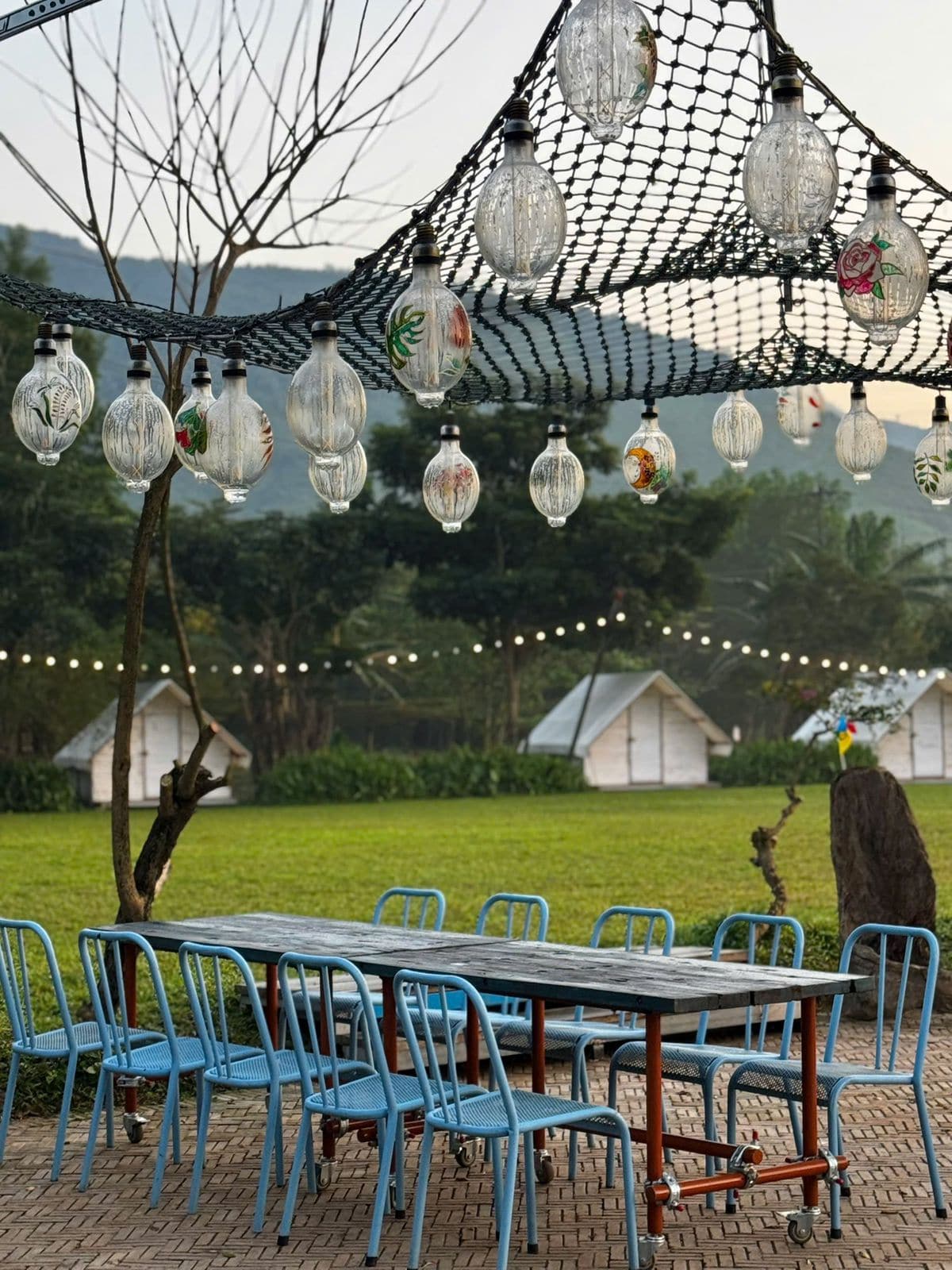 Outdoor retreat dining area with glass lanterns strung above a long table
