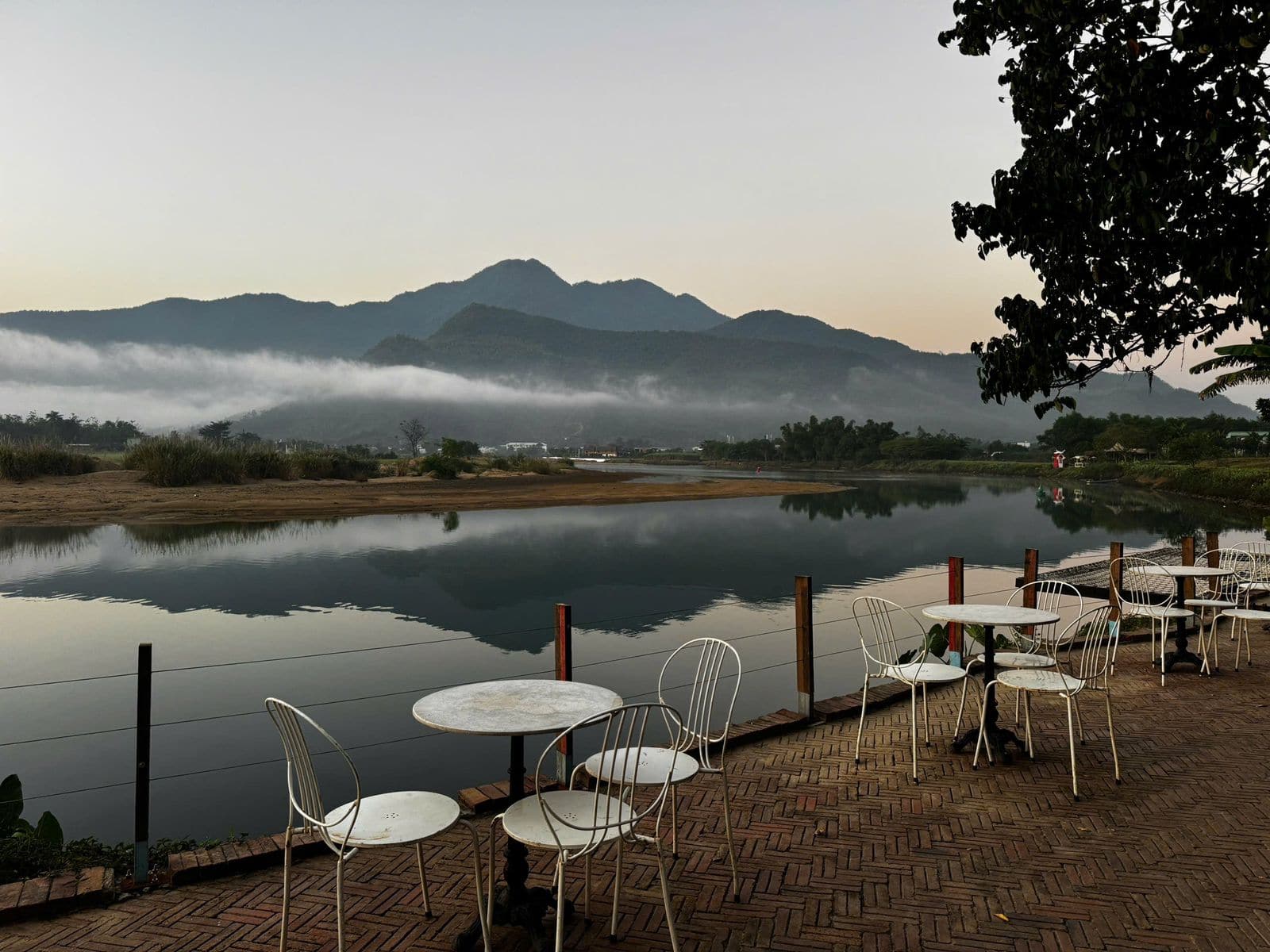 Riverside retreat terrace at dawn with mist lying over the mountains