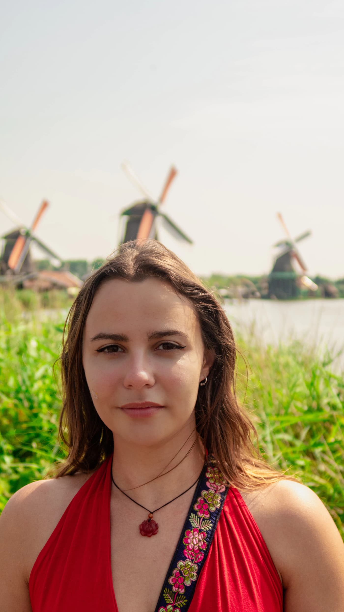 Portrait of Boyana Vancheva in a red dress in front of traditional Dutch windmills